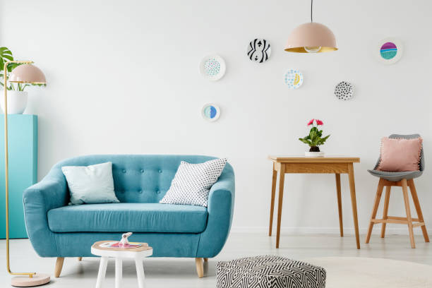 istock Comfy sofa, coffee table, pouf, wooden table and chair, and hanging patterned plates in a sweet living room interior 957769798