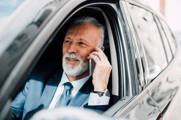 istock Business man using phone and smiling in a car 957769858