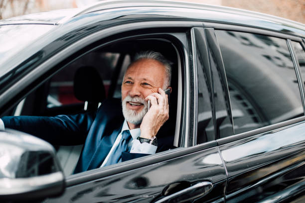 istock Happy senior business man using phone while driving a car 957769882