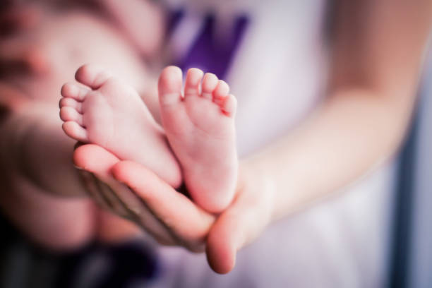 istock Baby feet in mother's hands 957770540