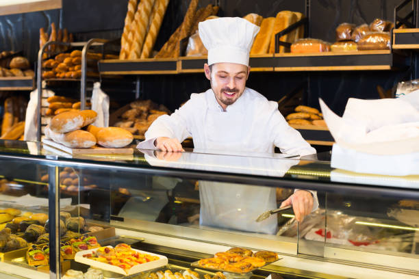 istock Smiling baker showing assortment of bakery 957778810