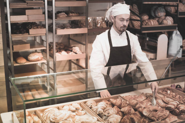 istock Smiling male pastry maker demonstrating croissant 957778826