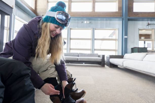 young woman putting on ski boots - snowboard boot imagens e fotografias de stock