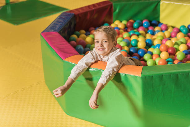istock cute little boy smiling at camera while playing in pool with colorful balls 957791496