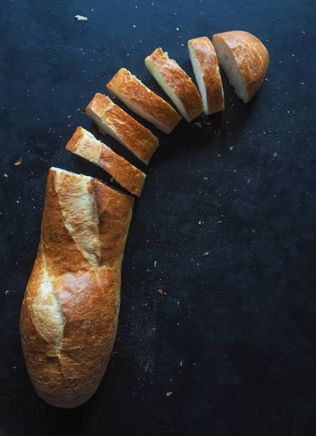istock Fresh, delicious baguette on the black table. Cut baguette. 957796840