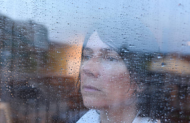 istock Woman looking out the window on a rainy day 957796934