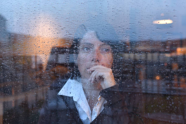 istock Woman looking out the window on a rainy day 957797176