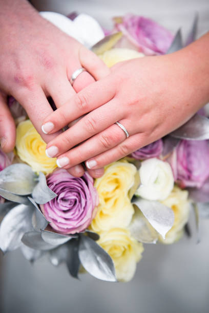 istock Bride and Groom Hands and rings on wedding bouquet 957805058