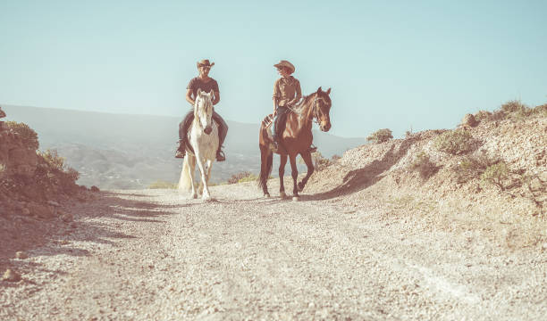 couple à cheval en visite de campagne nature - les gens heureux s’amuser le jour de l’été - vacances, excursion, mode de vie sain, sport, l’amour entre les humains et les animaux concept - focus sur le visage de l’homme - cowboy hat photos photos et images de collection