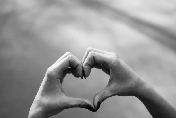 chica haciendo un corazón forma gesto contra el fondo gris del asfalto. - valentines day teenager passion romance fotografías e imágenes de stock