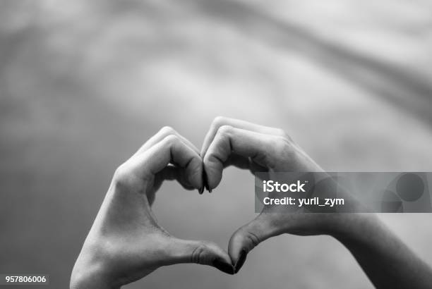 Girl Making A Heart Shape Gesture Against Grey Asphalt Background Stock Photo - Download Image Now