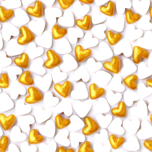 istock 3D small gold painted inflated handmade plasticine hearts mixed with white plain heart shapes paper cards as an empty space for text - seamless abstract pattern background 957810906