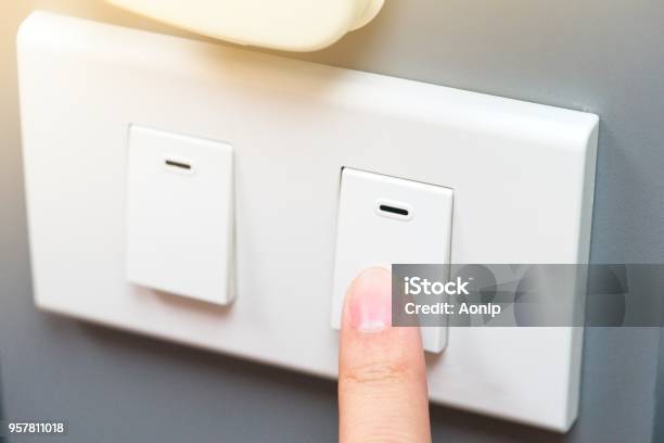 Saving Energy Concept Someone Trying To Use Index Finger To Pressing A Switch There Is Yellow Ray Light Located On Top Rigth Of Frame Stock Photo - Download Image Now