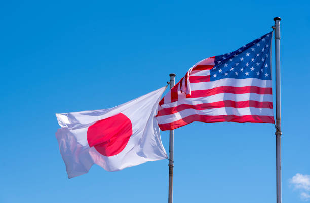istock American and Japanese Flags waving against blue Sky 957819534