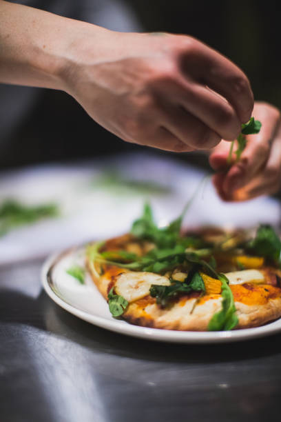 Cook preparing a pizza with cheese and vegetables. Restaurant and catering