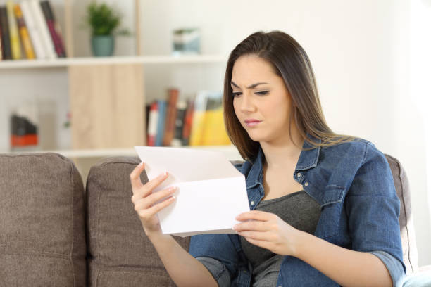 istock Suspicious female reading a letter at home 957824580