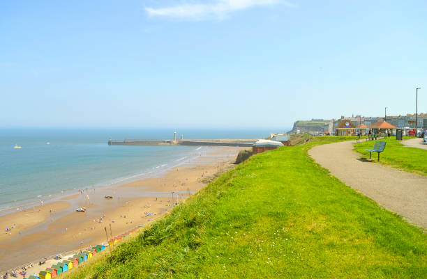 Whitby, North Yorkshire, England, UK - May 7, 2018 : Tourists on Whitby beach West Cliff in North Yorkshire