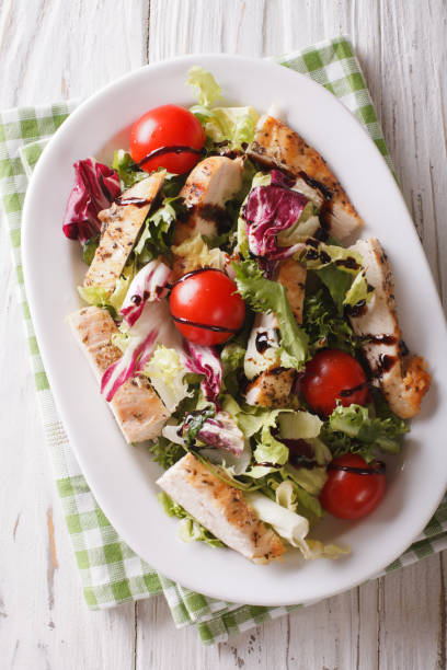 istock Sliced grilled chicken with mixed salad and tomatoes close-up. Vertical top view 957824972