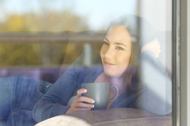 istock Relaxed woman looking outdoors through a window 957827990