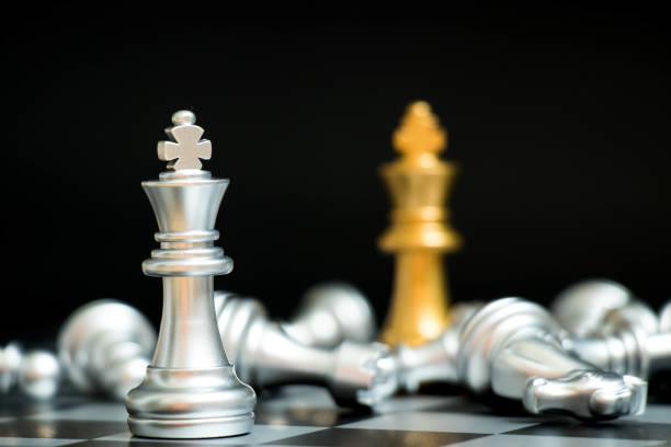 istock Gold king in chess game face with the another silver team on black background (Concept for company strategy, business victory or decision) 957828044