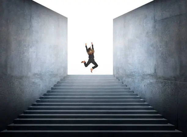 Photo of Businesswoman Jumps For Joy At The Top Of Steps