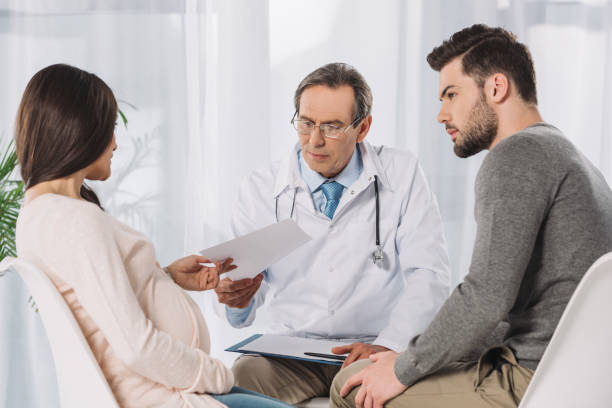istock doctor giving documents to couple expecting child 957833092