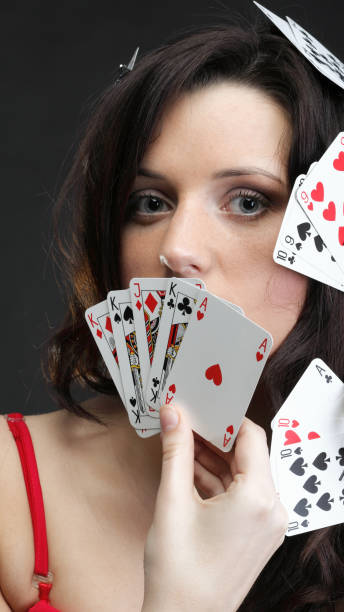 istock woman holding playing cards black background 957834194