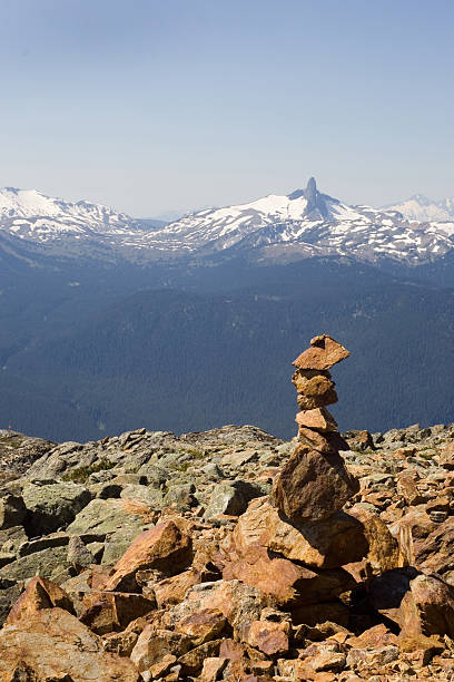 Twin Peaks, Whistler, British Columbia View at the top of Whistler Mountain.  Mother nature's peak- Black Tusk in the background, and a Manmade one- Inukshuk in the foreground..  inukshuk whistler cairn mountain stock pictures, royalty-free photos & images