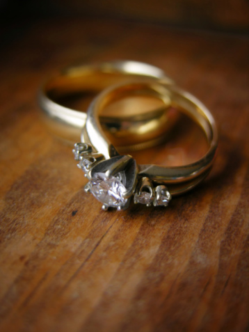 Wedding ring set with woman's diamond ring in focus in the front.