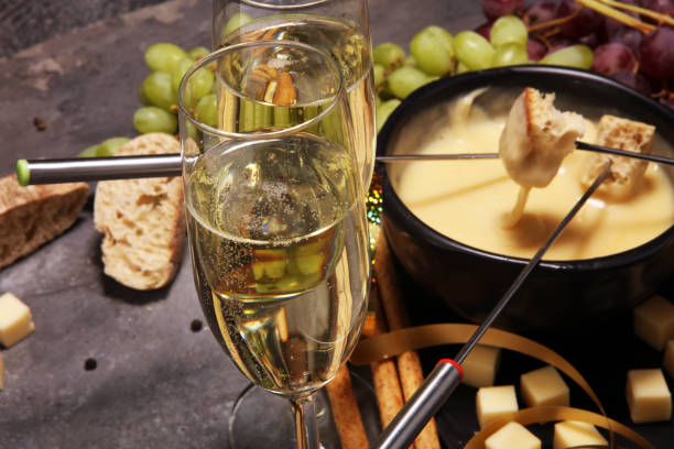 istock Gourmet Swiss fondue dinner on a winter evening with assorted cheeses on a board alongside a heated pot of cheese fondue 957837892