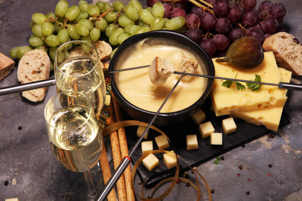 istock Gourmet Swiss fondue dinner on a winter evening with assorted cheeses on a board alongside a heated pot of cheese fondue 957838136
