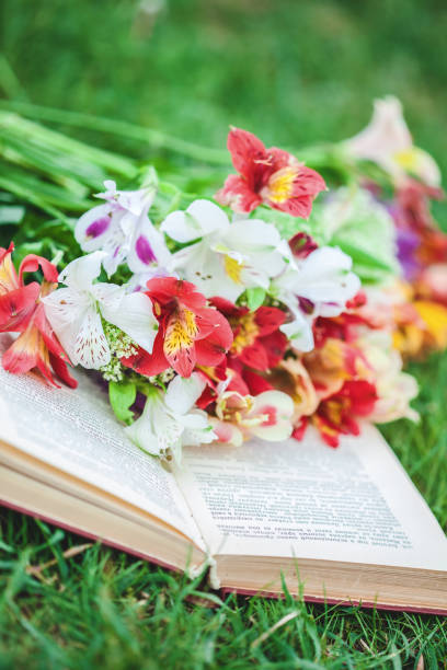 istock Beautiful flowers on the grass with a book. Close-up 957842192