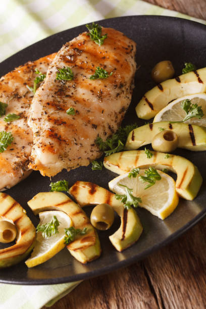 istock Grilled chicken breast with avocado, lemon and olive close-up. Vertical 957845000