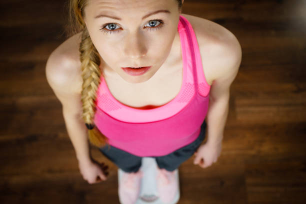 istock Teenage woman on bathroom scale machine 957849976