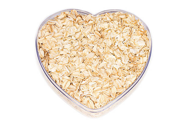 oatmeal für ein gesundes herz - oatmeal oat heart shape rolled oats stock-fotos und bilder