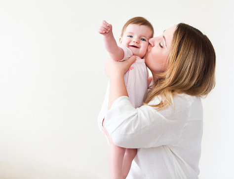 Young woman in the morning embrace and kissing with small girl. Happy family