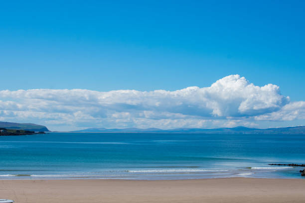 песчаный пляж и побережье океана на фоне ясного голубого неба в портруш северной ирландии. солнечный летний день - portrush стоковые фото и изображения