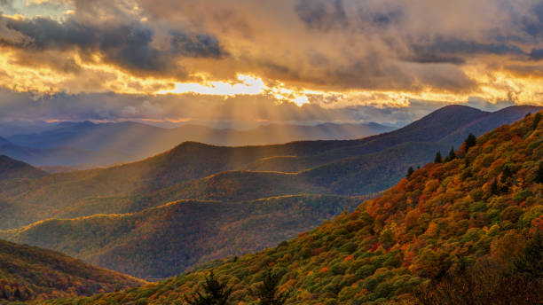 Dramatic Autumn Sunset on the Blue Ridge Parkway near Brevard North Carolina Dramatic sunset with strong shafts of light highlighting the mountains vast blue ridge sunset stock pictures, royalty-free photos & images