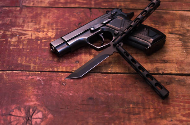istock Butterfly knife and black pistol. 957900106