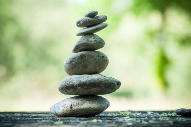 istock stones balance on wooden table on green blurred background 957901598