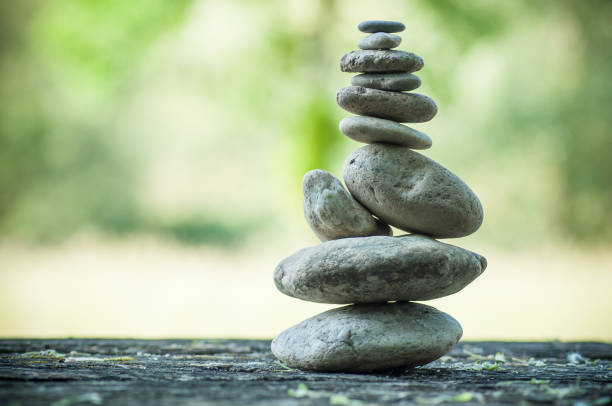 istock stones balance on wooden table on green blurred background 957903648