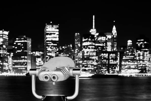 Black and white picture of binoculars pointed at Manhattan skyline at night, New York City, USA.