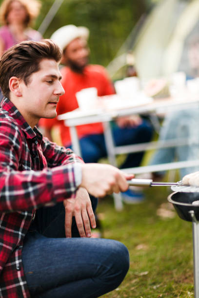 istock Young Man Grilling In Park With Friends 957952950