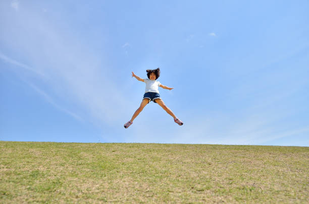 istock Girl's jumping in the blue sky 957961308