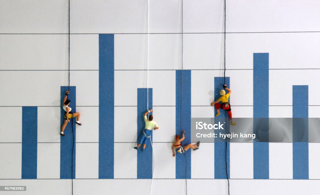 The miniature climbers use a rope to climb the blue bar graph. A competitive concept for promotion in the workplace. Wealth Stock Photo