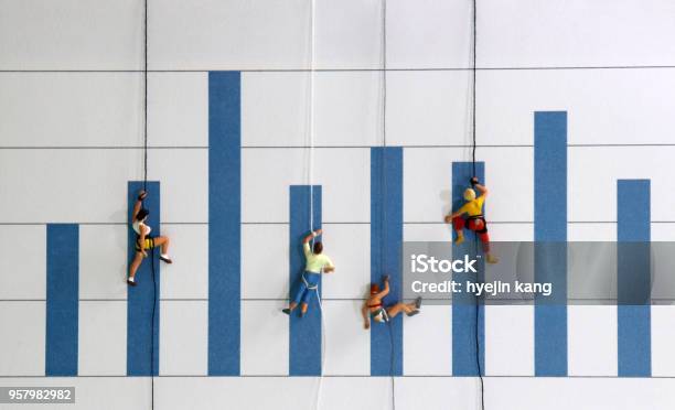 The Miniature Climbers Use A Rope To Climb The Blue Bar Graph A Competitive Concept For Promotion In The Workplace Stock Photo - Download Image Now