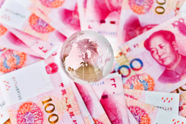 istock Glass globe and Chinese yuan notes 957983542