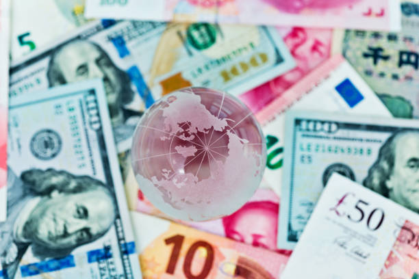 istock Glass globe and international currency notes 957983636