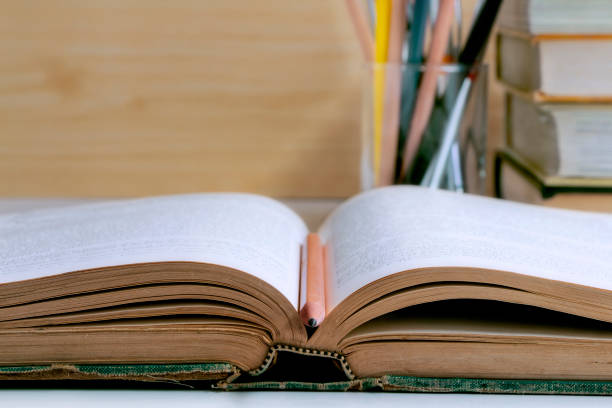 istock Open hardback and textbook stacked on the table background. The concept of intelligence comes from education. Selective focused on the textbook. 957986958