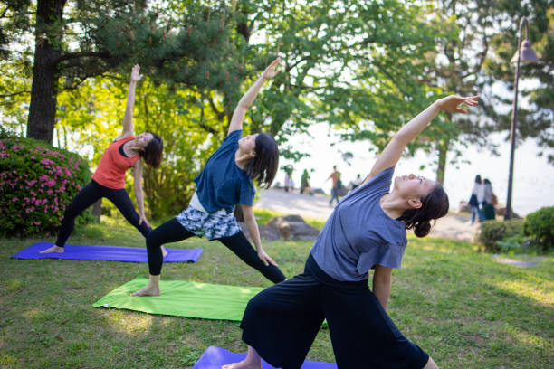 istock Three women practicing yoga in public park 957987472